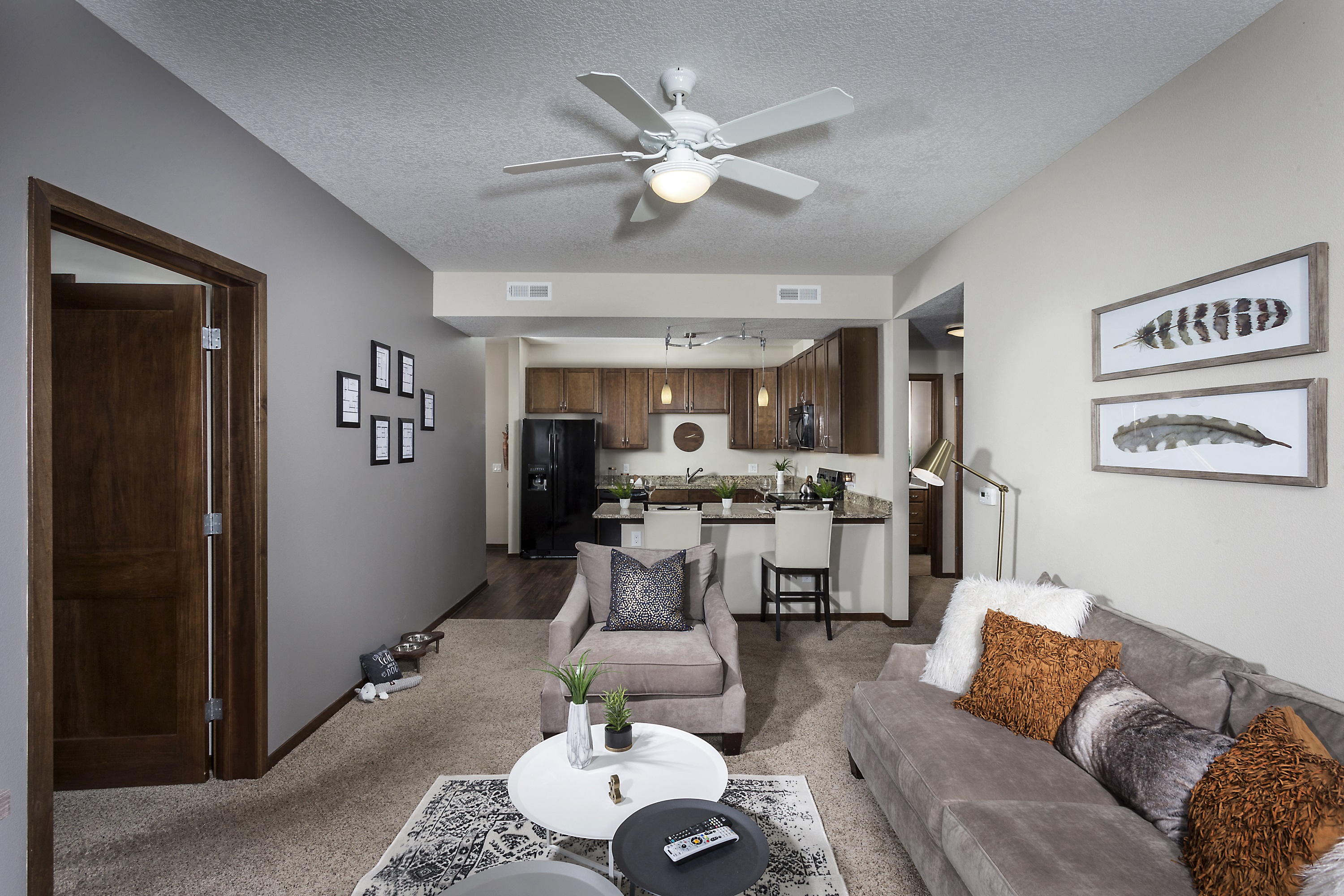large living room with ceiling fans, kitchen counters, and cozy furniture