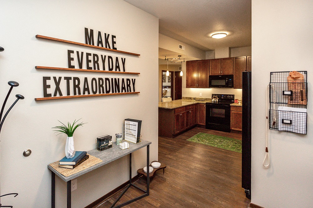 entryway into apartment unit with sign 'Make Everyday Extraordinary' and view into the kitchen