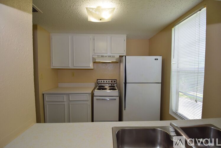 A kitchen with a white refrigerator, a white stove, and white cabinets.