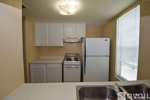 A kitchen with a white refrigerator, a white stove, and white cabinets.