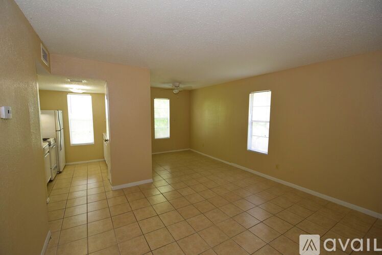 A spacious room with tile flooring and a few windows.
