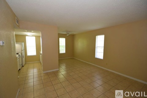 A spacious room with tile flooring and a few windows.