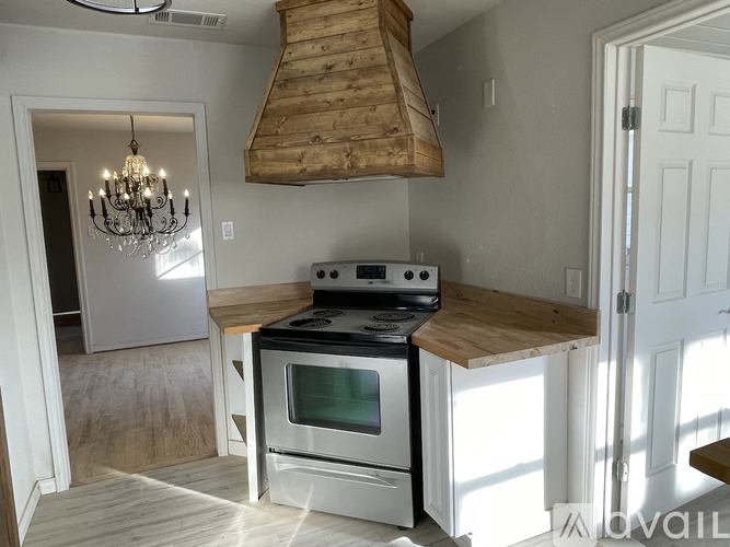 A kitchen with a stove top oven and a chandelier.