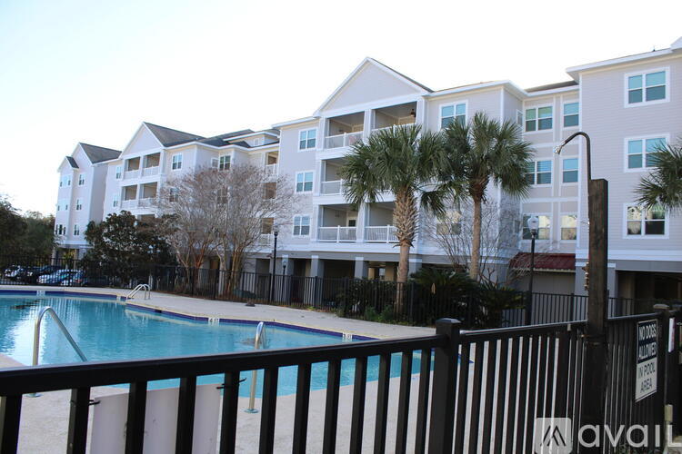 A pool in front of a building with a black fence.
