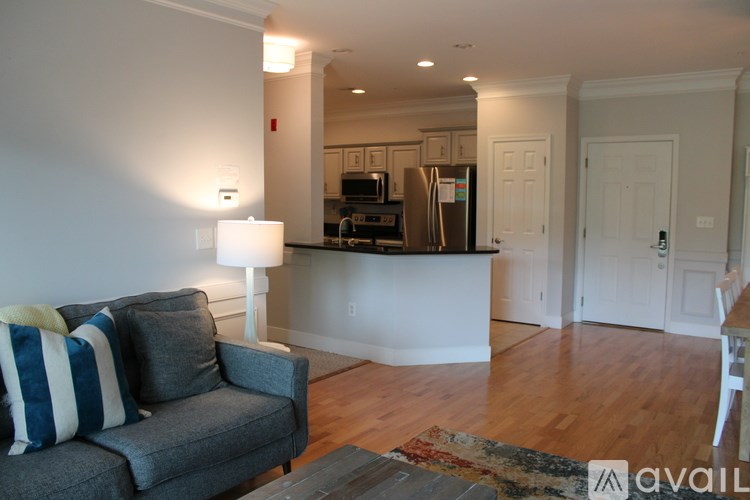 A living room with a grey couch and a white lamp.