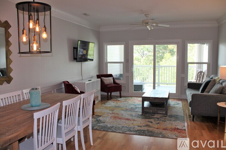 A living room with a wooden table and chairs, a television, and a rug.