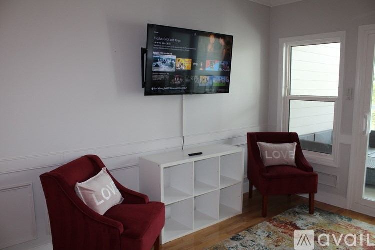 A living room with a red chair and a TV mounted on the wall.
