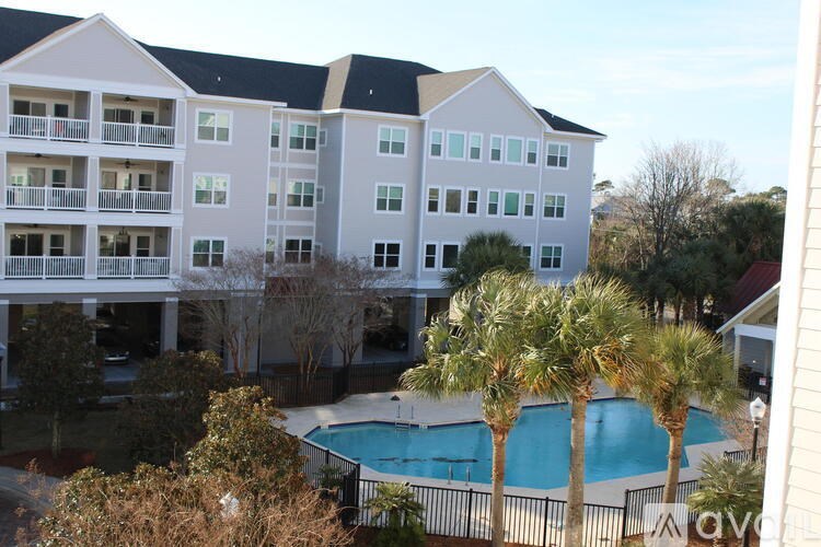 A large apartment complex with a pool and palm trees.