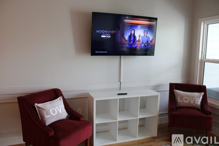 A living room with a red chair and a television showing a show called Moonshot.