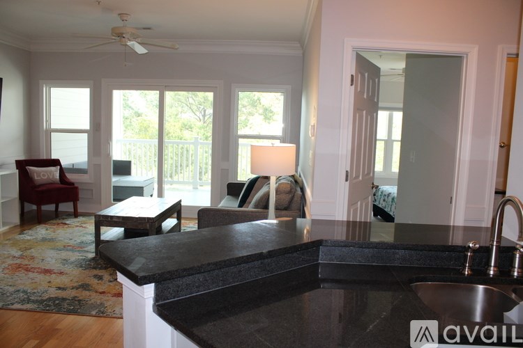 A kitchen with a black counter top and a ceiling fan.