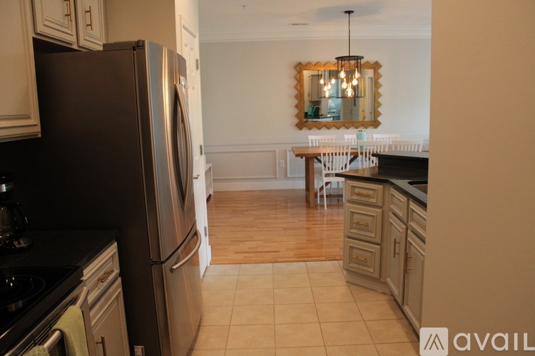 A kitchen with a refrigerator, stove, and a dining table with chairs.