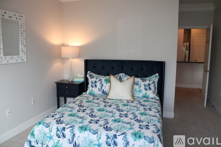 A bed with a floral patterned comforter and a black headboard.