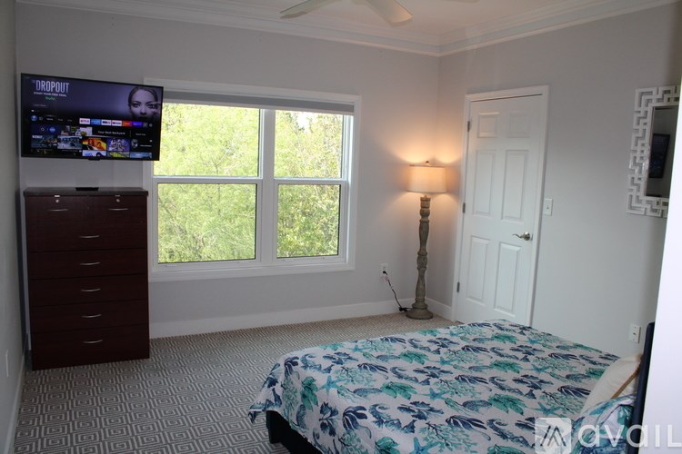A bedroom with a bed, dresser, and window.