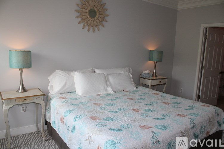 A bed with a floral patterned comforter sits in a room with two lamps on either side.