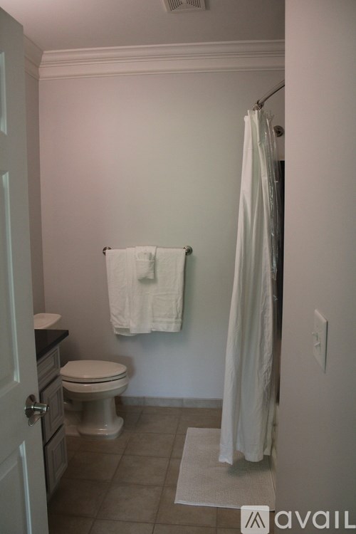 A white bathroom with a toilet, a towel, and a shower curtain.