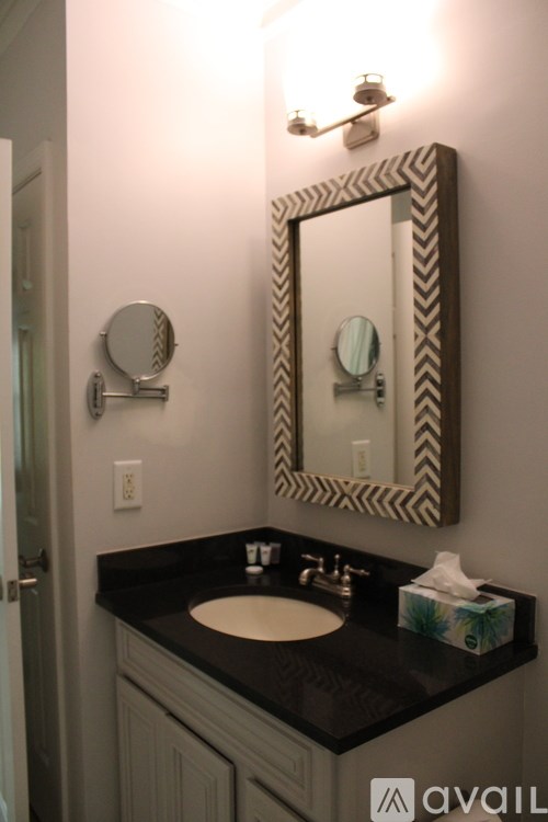 A bathroom with a sink, mirror, and light.
