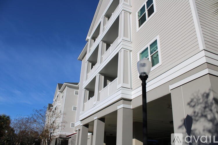 A tall white building with balconies and a street lamp in front.