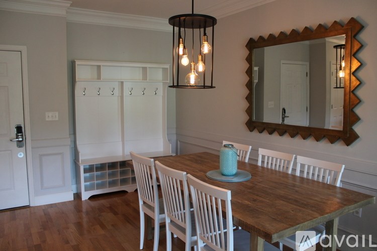 A dining room with a wooden table and white chairs.
