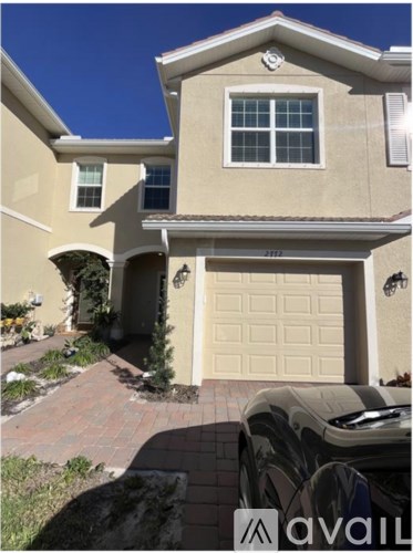 A beige house with a garage door and a car parked in front.