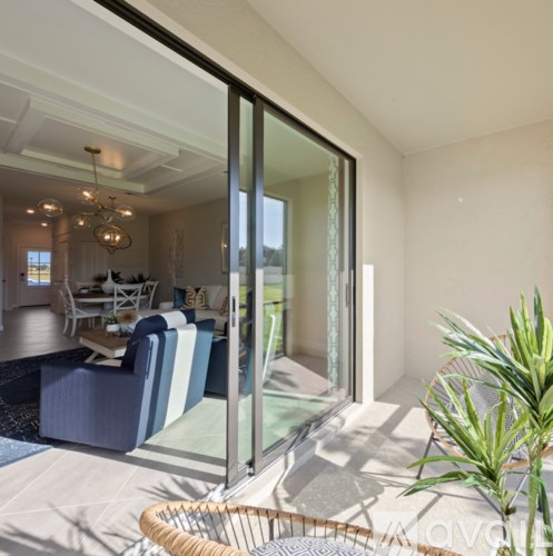 A living room with a blue couch and a glass door leading to a balcony.
