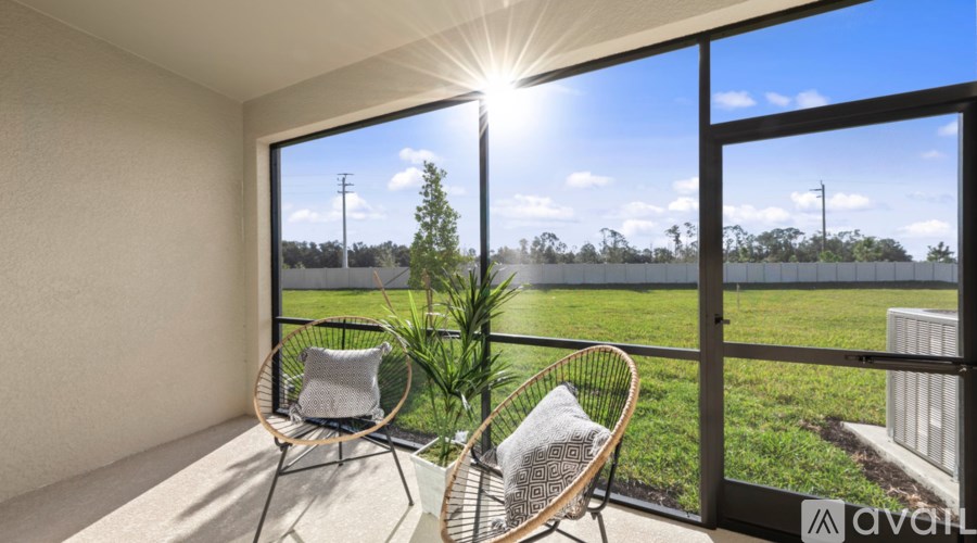 A balcony with two chairs and a table is bathed in sunlight.