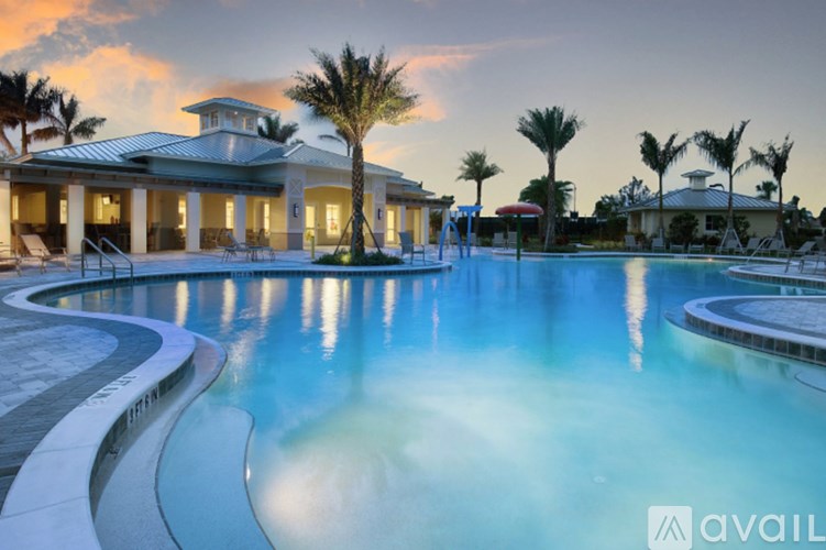 A pool with a building behind it and palm trees around it.