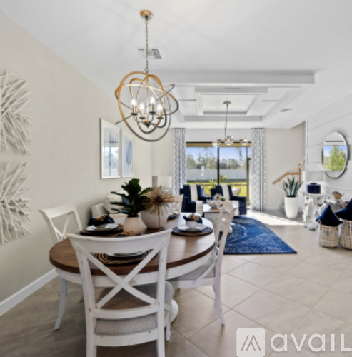 A dining room with a wooden table and white chairs.