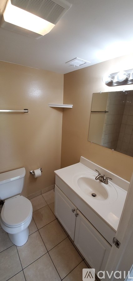 A bathroom with a toilet, sink, and mirror.