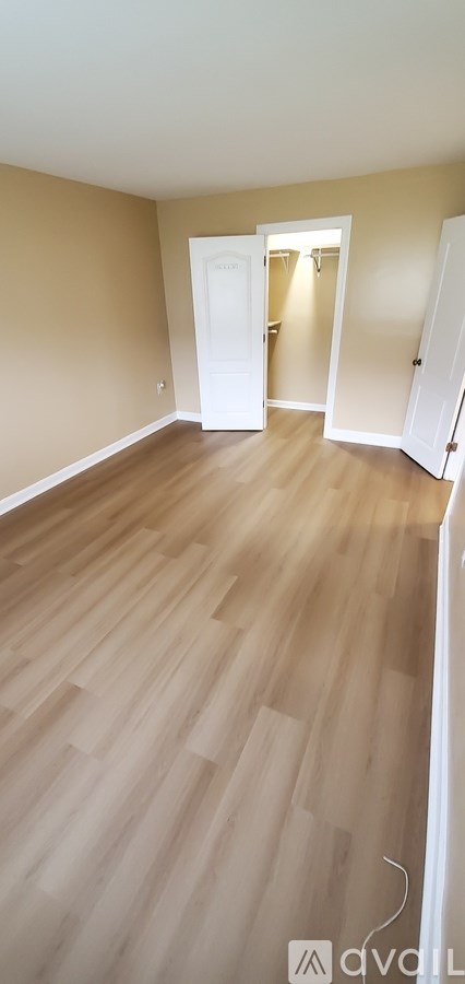A room with wooden flooring and a white door.