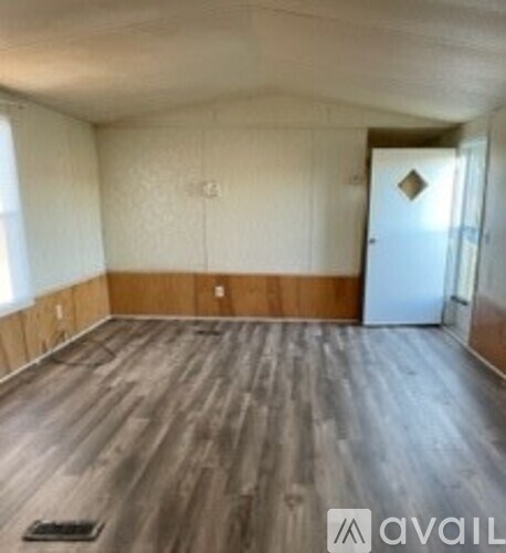 A room with wooden flooring and a door on the right side.