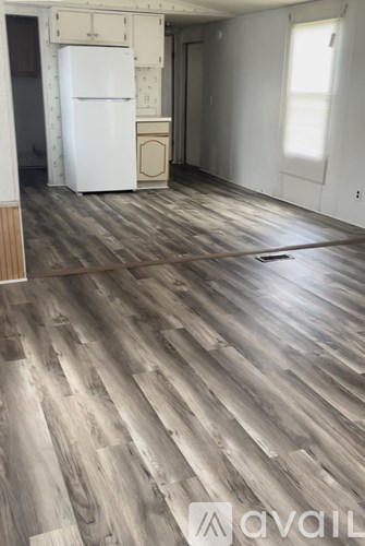 A room with wooden flooring and a white fridge.