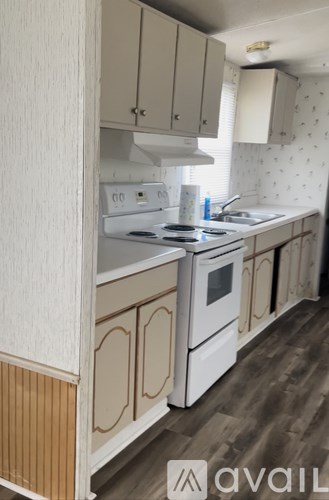A kitchen with white appliances and wooden floors.