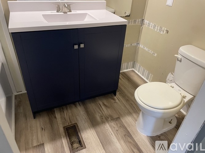 A bathroom with a white toilet and a white sink with a cabinet underneath it.