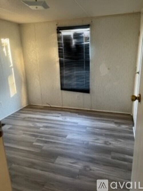 A room with wooden flooring and a window covered with blinds.