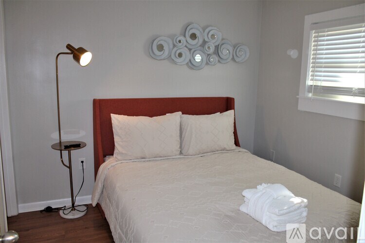 A bedroom with a bed, a lamp, and a wall decoration.