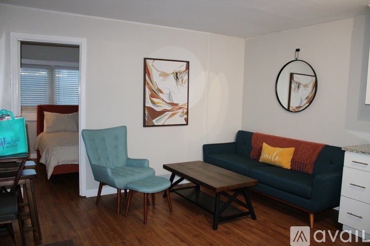 A living room with a blue couch and a painting on the wall.