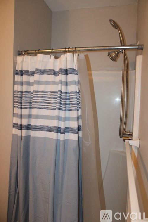 A shower curtain with blue and white stripes hangs on a silver rod.