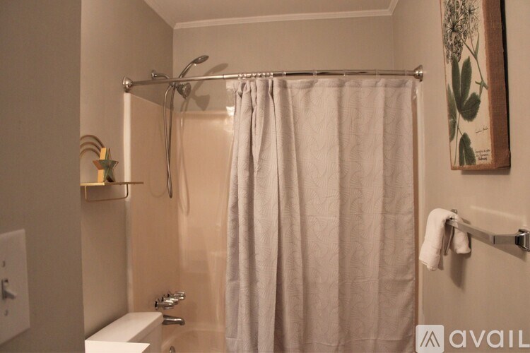 A bathroom with a white shower curtain and a white towel hanging on the towel rack.