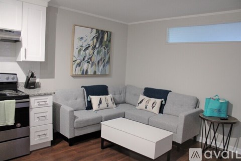 A modern living room with a grey couch, a white coffee table, and a painting on the wall.