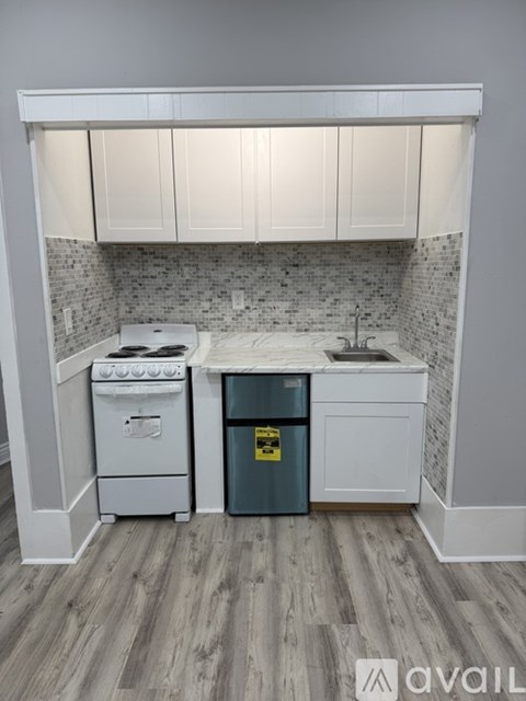 A kitchen with a white oven and a green trash can.