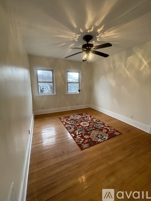 A room with a ceiling fan and two windows.