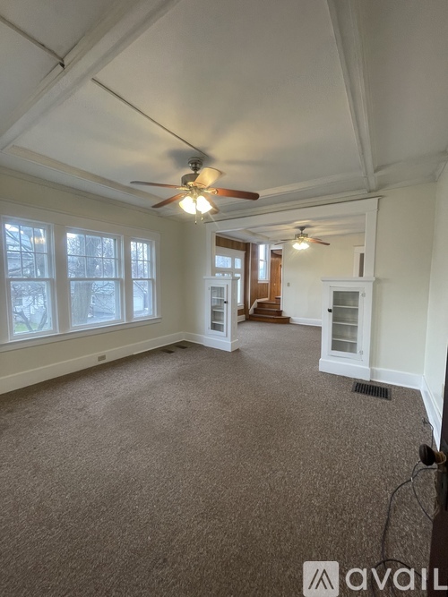 A spacious room with a carpeted floor and a ceiling fan.