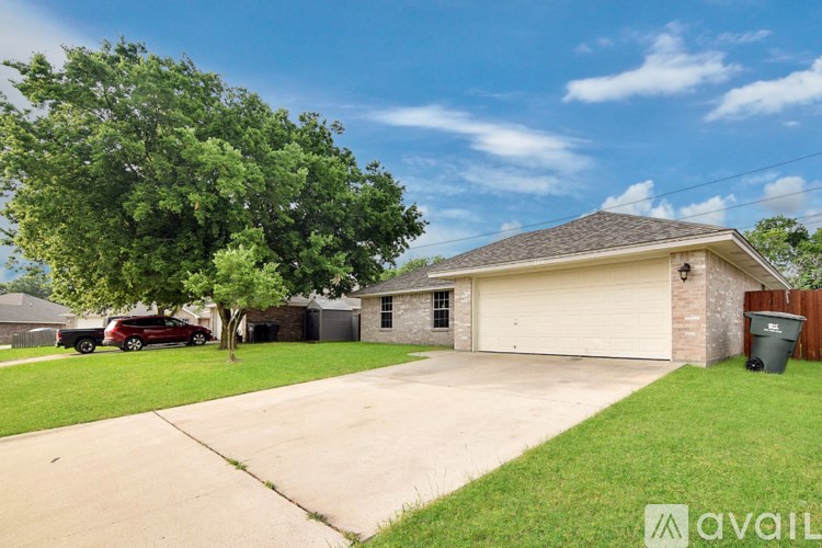 A house with a driveway and a tree in front of it.