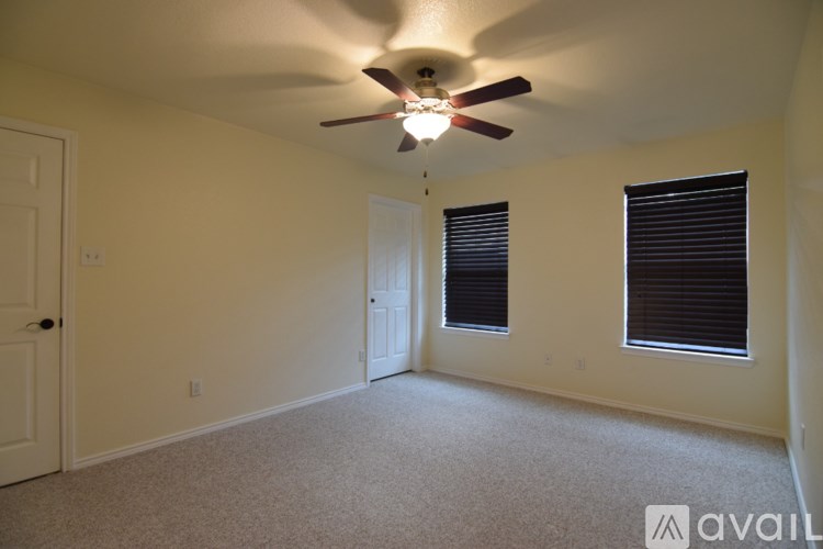 A room with a ceiling fan and two windows with blinds.