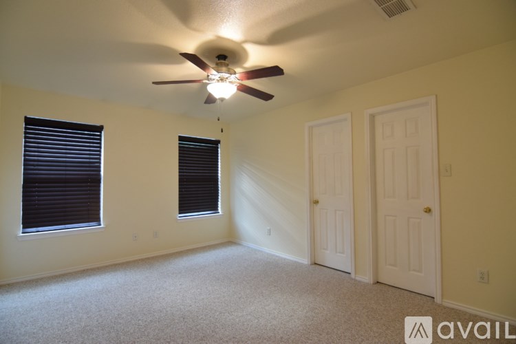 A room with a ceiling fan and two doors.