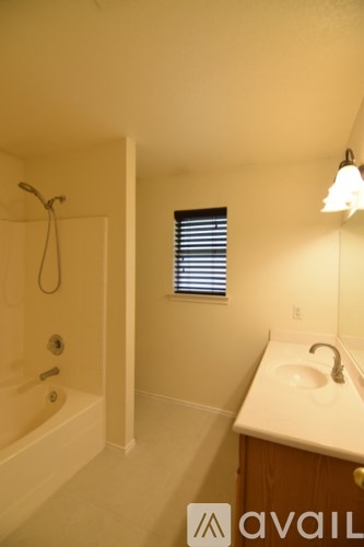 A bathroom with a tub, sink, and window.