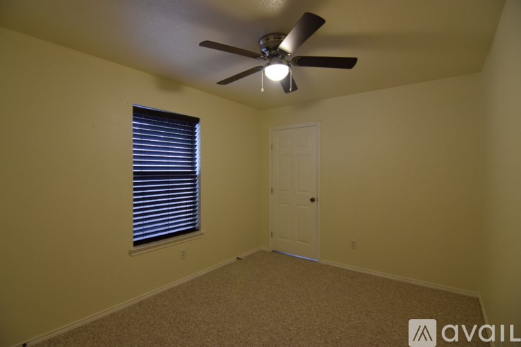 A room with a ceiling fan and a window with blinds.