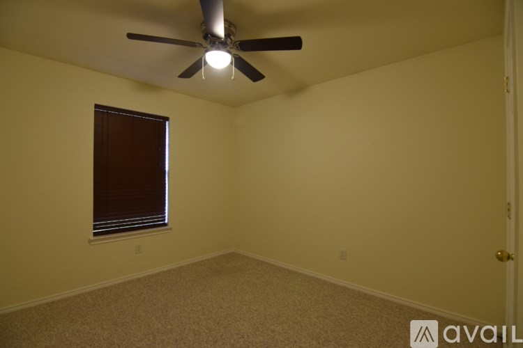A room with a ceiling fan and a window with blinds.