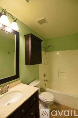 A bathroom with a toilet, sink, and mirror.