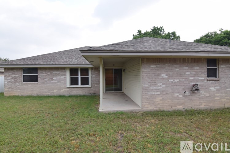 A house with a grey roof and a brown brick wall is available for rent.